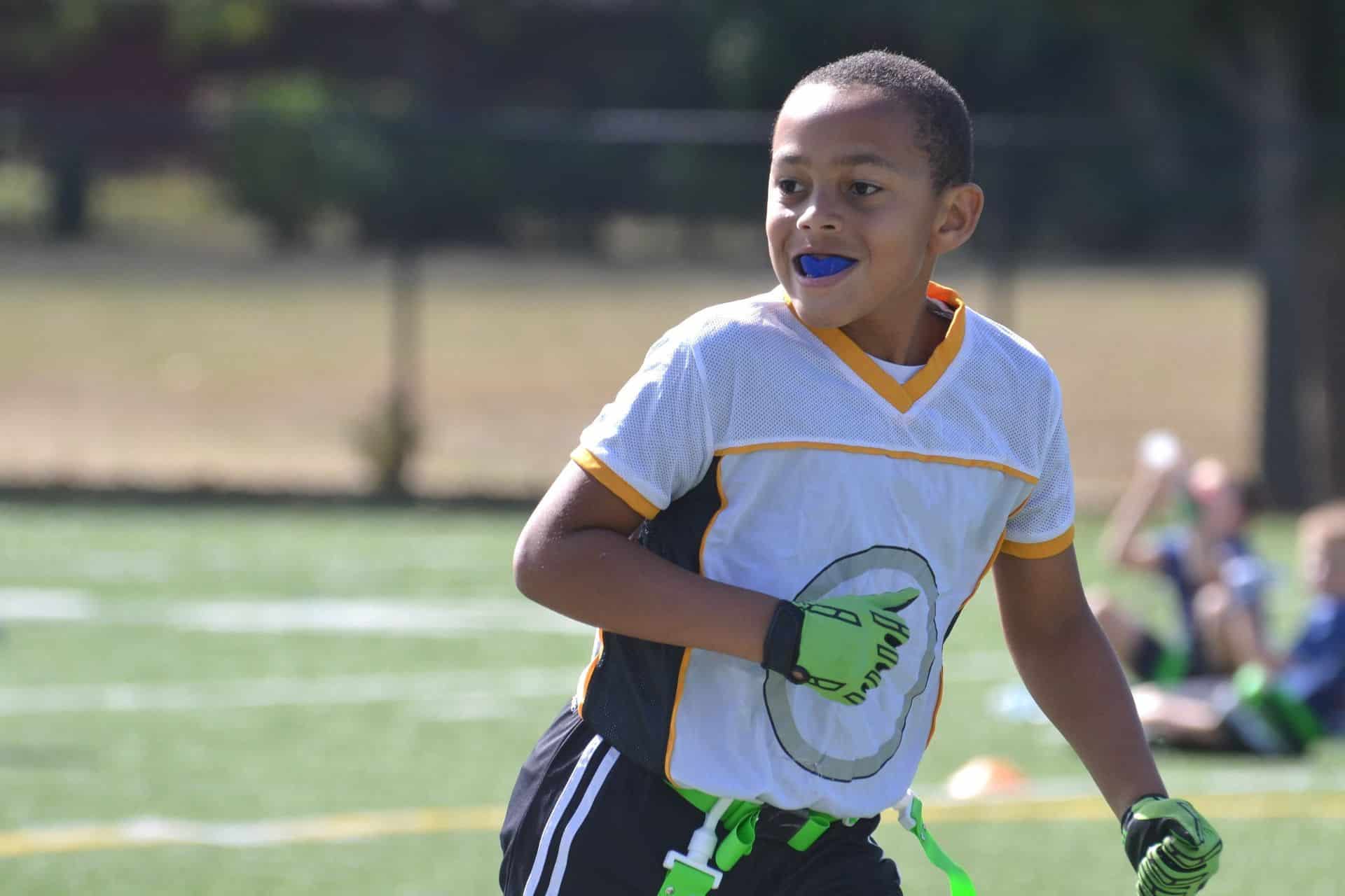 Child athlete wearing a mouthguard while playing flag football