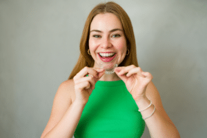 Adult holding clear aligners for Invisalign treatment in Lake Worth, FL