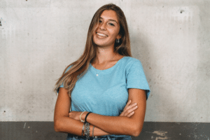 Young woman showing off a straight, healthy smile while standing with folded arms.