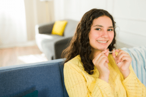 Smiling teen holding a clear orthodontic aligner